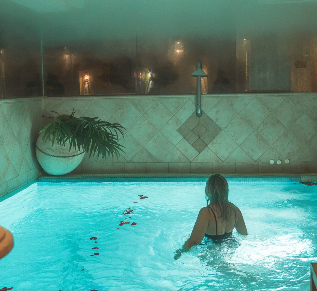 Mujer adentrándose en la piscina termal de Arte Vida